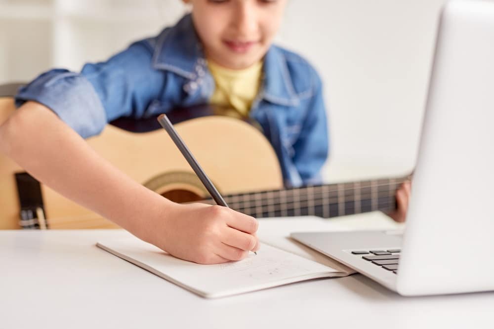 Garota fazendo anotações durante aula de violão ajudando na memoria