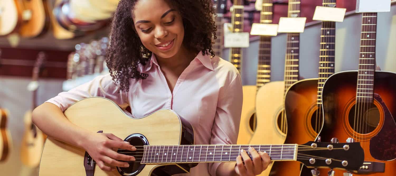 mulher-decidindo-e-tocando-violão-na-loja