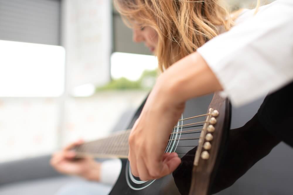 mulher tocando violão com a mão esquerda