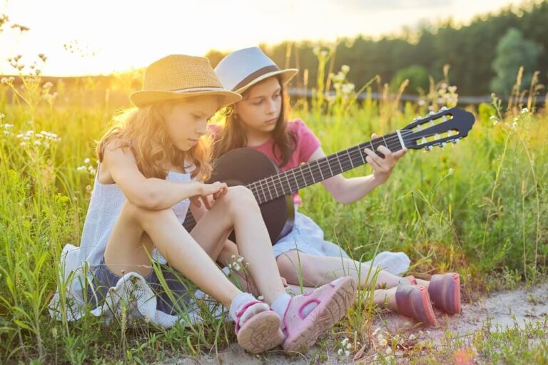 Crianças sentadas na natureza com violão clássico