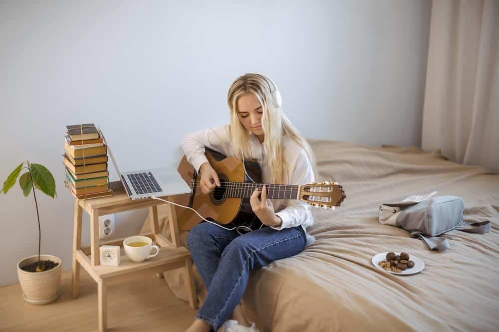 Mulher aprendendo a tocar violão em casa