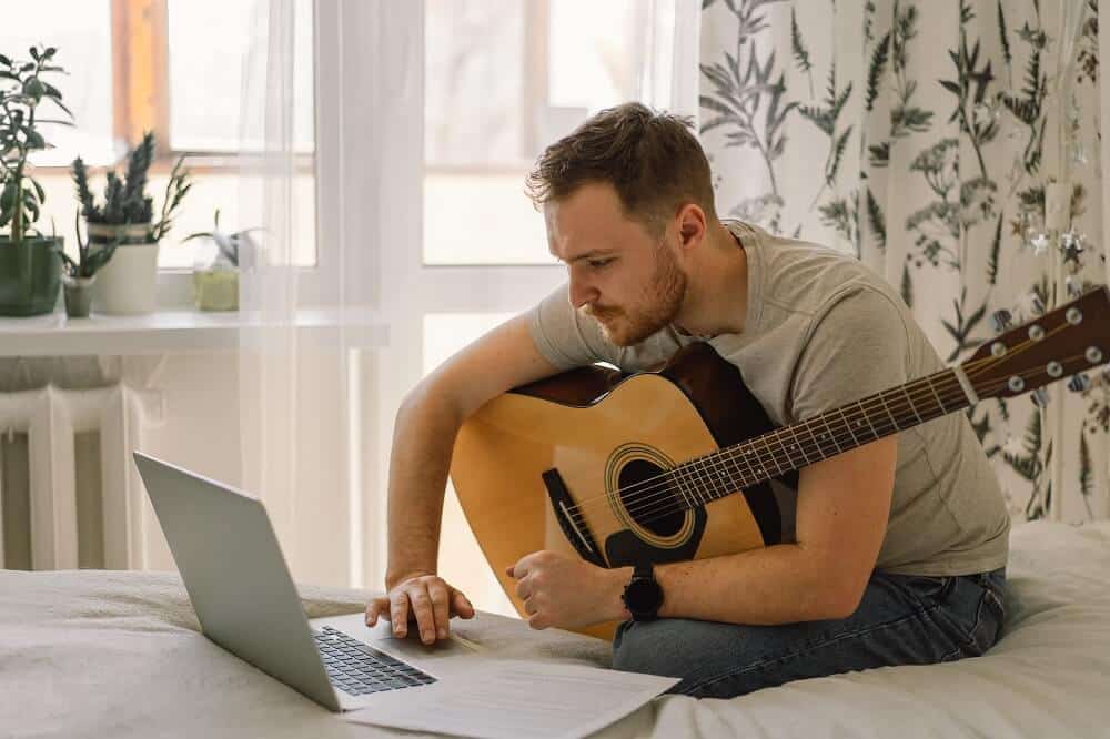 Homem toca violão em uma aula online