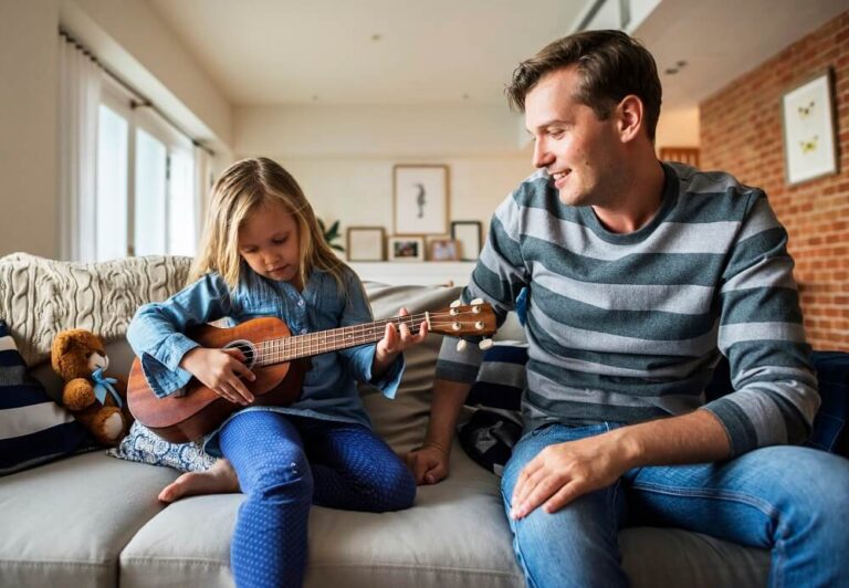 criança tocando violão com o pai em casa
